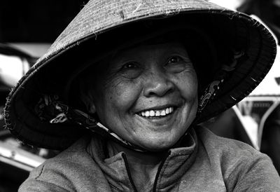 Close-up portrait of smiling senior woman wearing hat while sitting outdoors