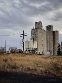 Factory on field against sky