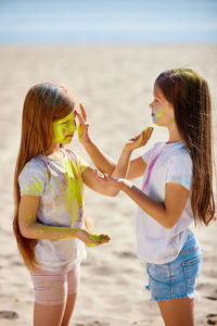 Side view of mother and daughter standing at beach