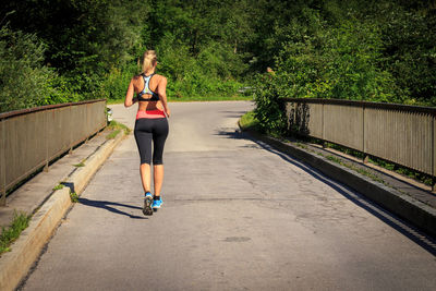 Full length rear view of woman running on walkway