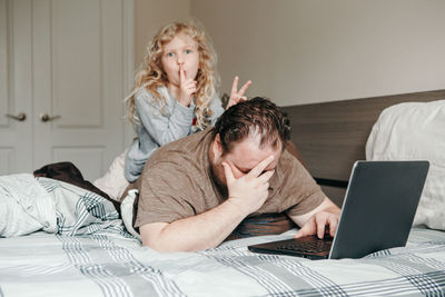 Work from home with kids children. father working on laptop with child daughter on his back. 