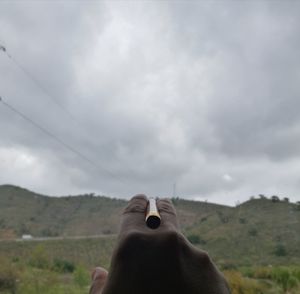 Person holding umbrella on landscape against sky