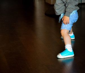 Low section of baby wearing shoes on hardwood floor
