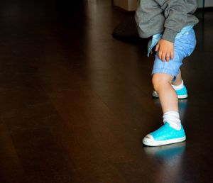 Low section of girl wearing shoes on floor