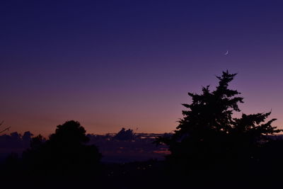 Silhouette trees against clear sky at sunset