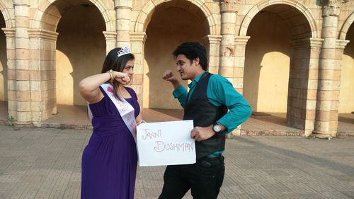 Bride and friend gesturing while holding paper against building