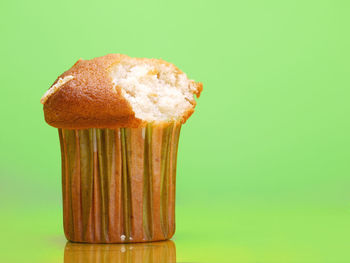 Delicious cupcake with bite taken shot on light green background