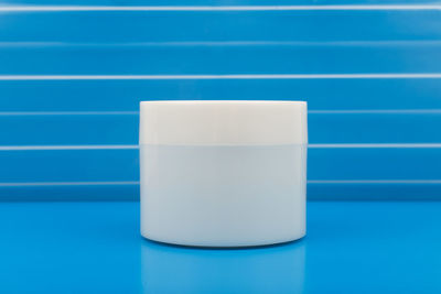 Close-up of white cup on table against blue background