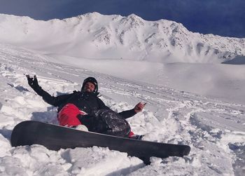 Man lying while snowboarding on snow covered mountains during winter