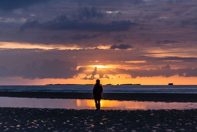 Woman standing at beach during sunset