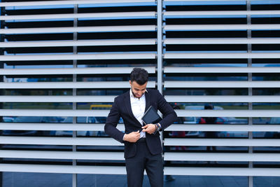 Young businessman standing by wall