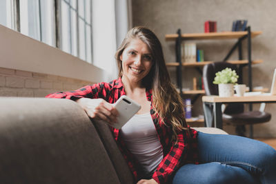 Portrait of smiling woman sitting on sofa at home