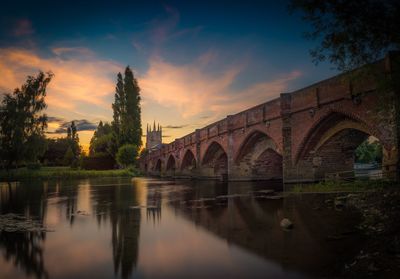 Reflection of bridge on water against sky