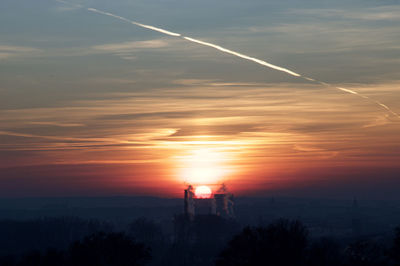 Scenic view of vapor trails in sky at sunset