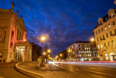 Light trails on city street amidst buildings at night