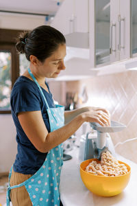 Side view of woman preparing food in kitchen