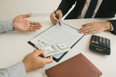 Midsection of man holding paper with text on table