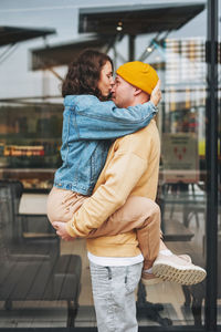 Happy stylish young family couple in love hipsters having fun against glass wall