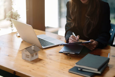 Midsection of woman using laptop on table