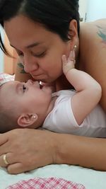 Mother playing with cute girl on bed at home