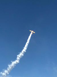 Low angle view of airplane flying against blue sky