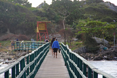 Rear view of man walking on footbridge