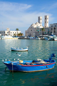 Boats moored in sea against buildings in city