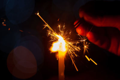 Cropped image of person burning sparklers at night