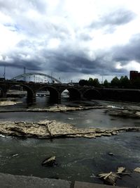 Bridge over river against cloudy sky