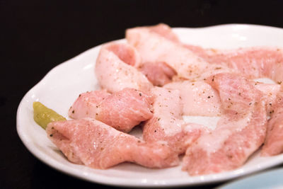 Close-up of meat in plate against black background