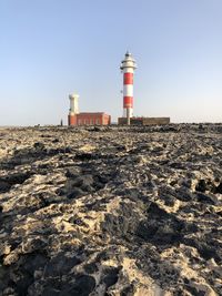 Lighthouse on beach against sky