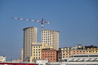 Low angle view of crane on building against clear blue sky