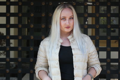 Portrait of beautiful young woman standing against wall