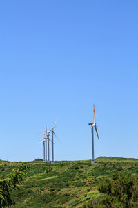 Wind turbines on field against clear blue sky