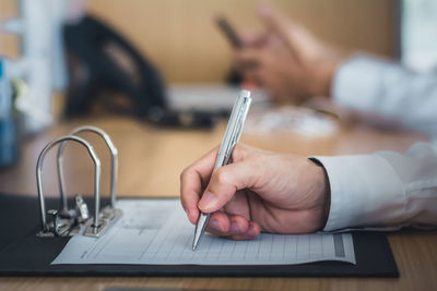 Cropped hand of woman writing in book