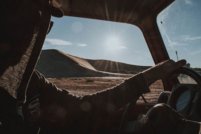 Man looking at bright sun through window while driving car 