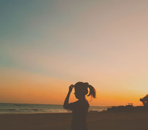 Silhouette man standing on beach against sky during sunset