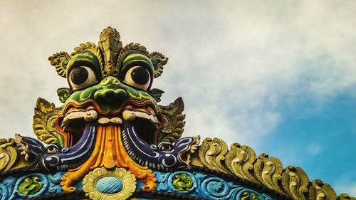 Low angle view of carved valluvar kottam entrance against cloudy sky