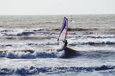 Man surfing in sea against sky