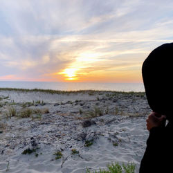 Man looking at sea against sky during sunset