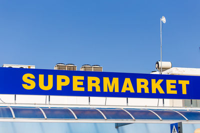 Low angle view of information sign against clear blue sky