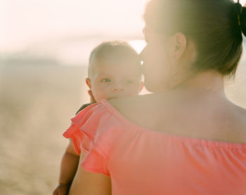 Close-up of mother holding son at beach during sunny day