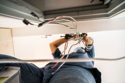 Wires with air conditioner technician repairing in the background. low angle view.