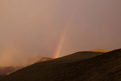 Rainbow over mountain against sky during sunset