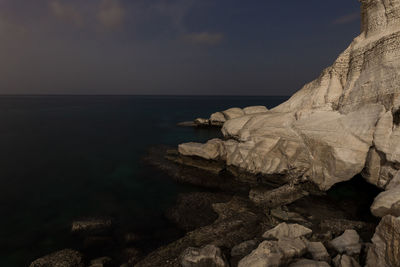 Rock formation on sea shore against sky