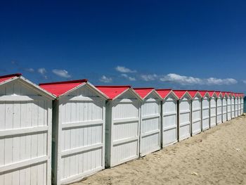 Row of red flags on beach against sky
