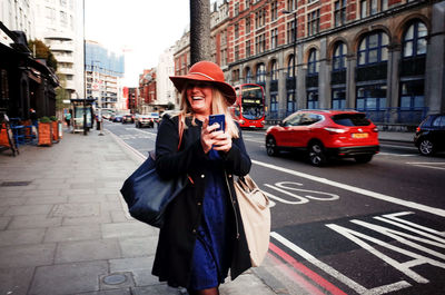 Young woman using phone while standing on street