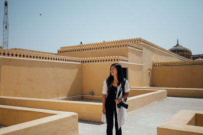 Full length of woman standing against building