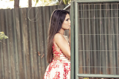 Portrait of beautiful young woman standing against wall