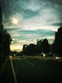 Cars on road against cloudy sky